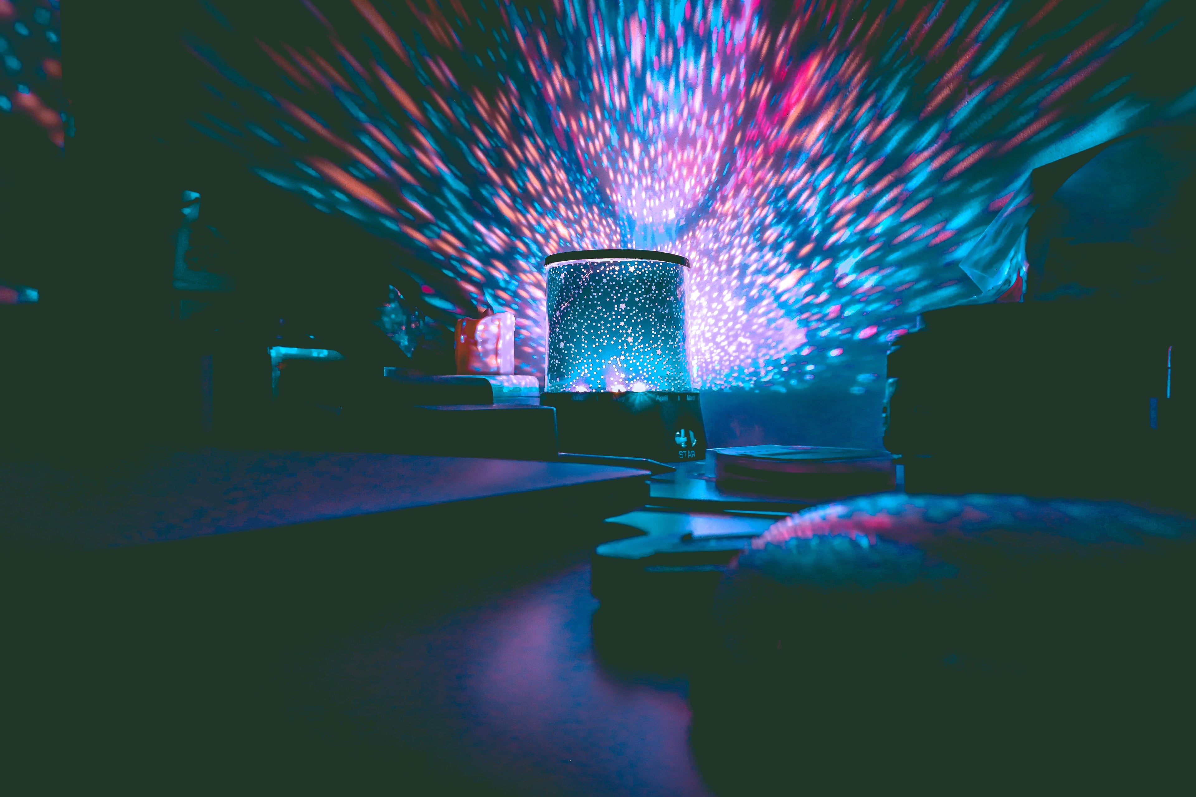 Galaxy projector filling a dark room with colorful stars